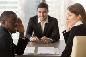 Two interviewers whisper skeptically about the job candidate across the desk.